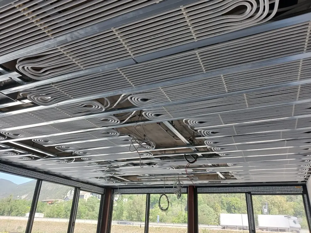 Weiße Rohrregister an der Decke zwischen Metallprofilen vor einer Fensterfront